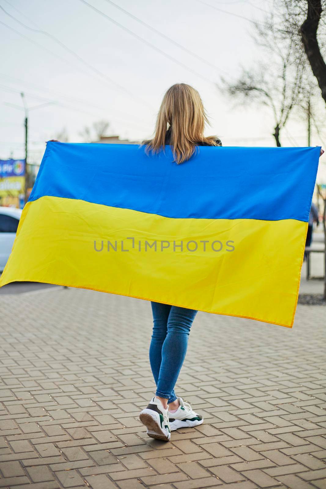 Portrait of a joyful Ukrainian woman holding a Ukrainian flag and a sign. The girl is waiting for her husband from the war. War between Russia and Ukraine