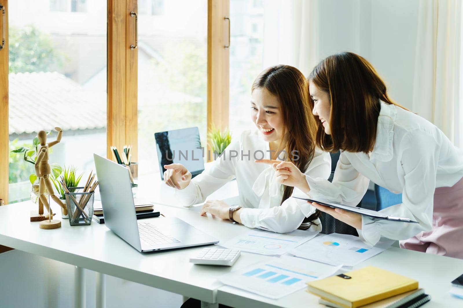 Consulting, learning, marketing, investment, finance, data analysis, research, two Asian women smiling pointing computer , sitting and analyzing financial statements and using computers at work