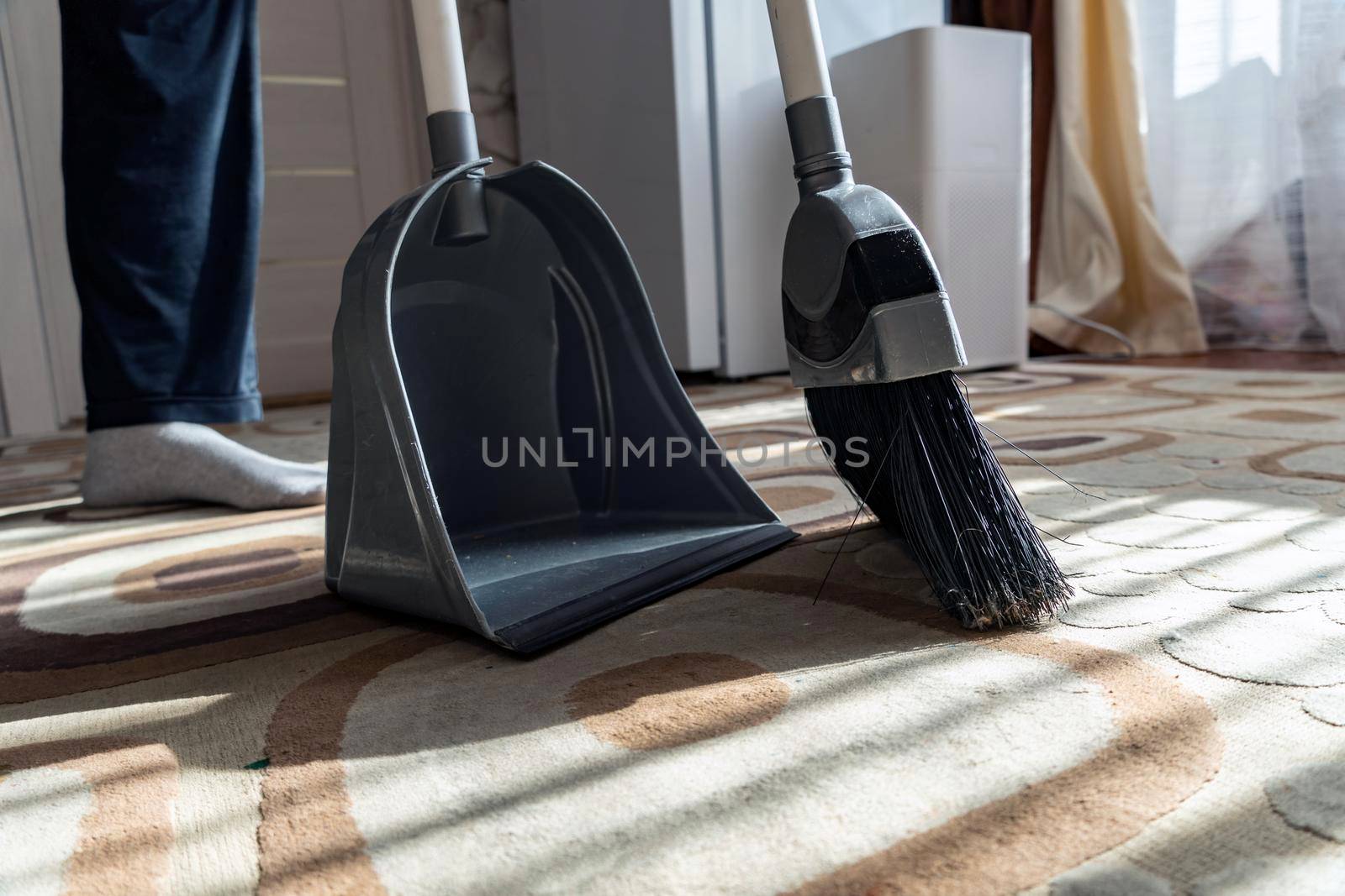 Cleaning.Clean up the garbage from the floor with a broom for cleanliness.Sweep away dust and dirt with a brush into a dustpan.Sweeping the carpet with a broom at home.Indoor cleaning tools.