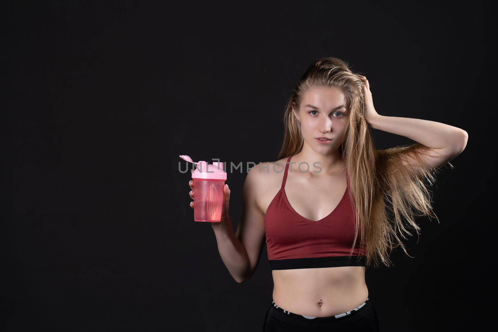 Spotrsman shaker holds a girl hand in her pink in black background shaker pink fitness body, In the afternoon female woman for young for bodybuilding isolated, beautiful people. Care ABS empty space