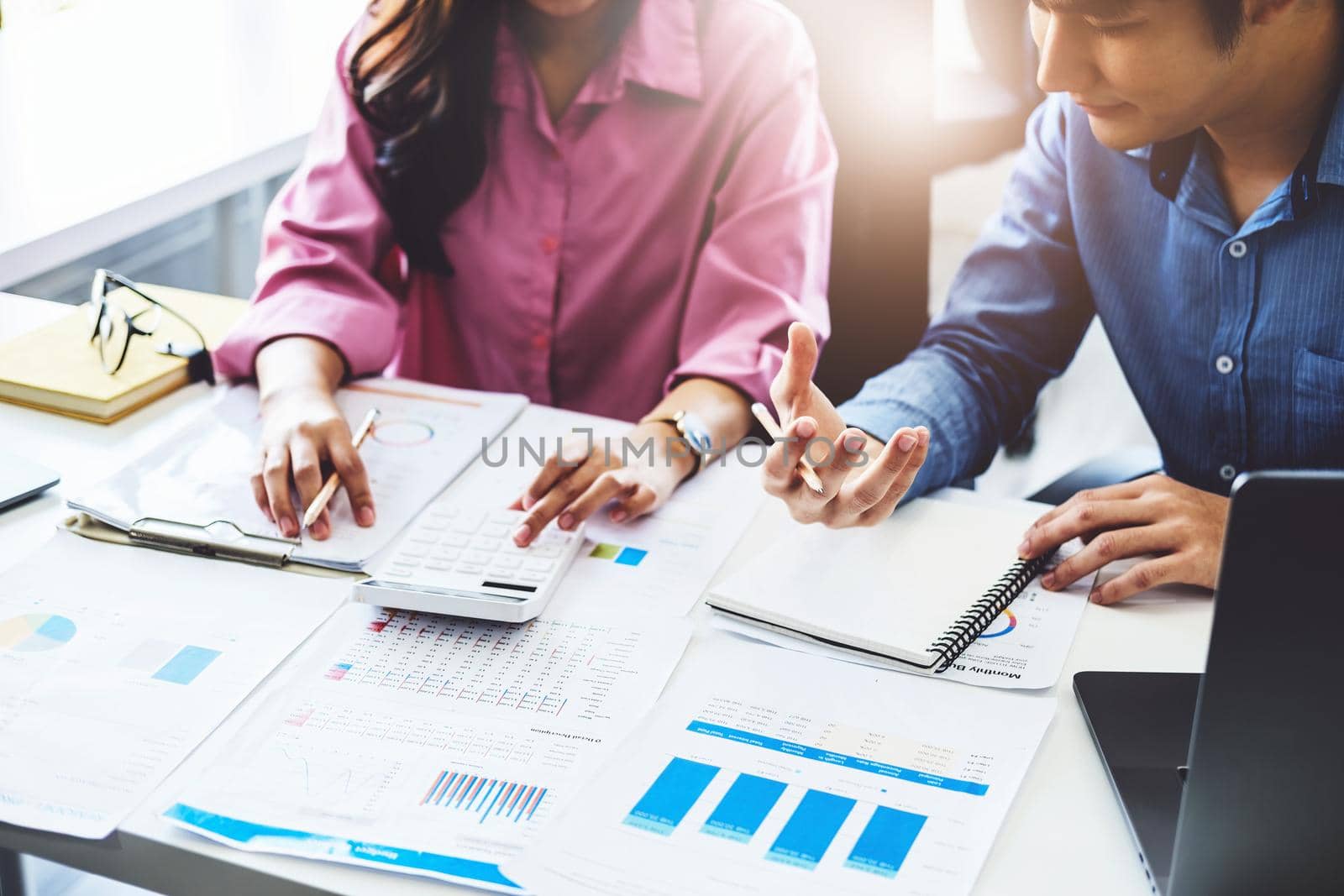 negotiation, analysis, discussion,asian male economist pointing out a document explaining the investment finance program to the company owner to plan marketing and hedging business risks. by Manastrong