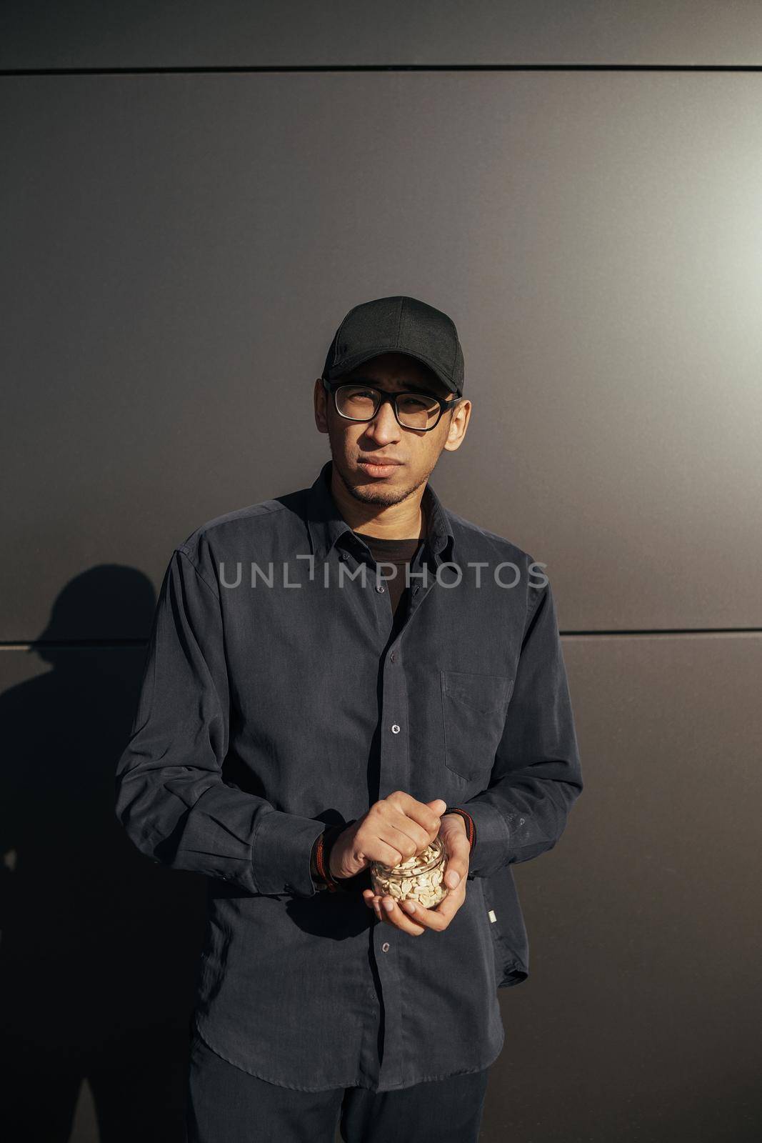 Young african american man holding peanuts on black background street