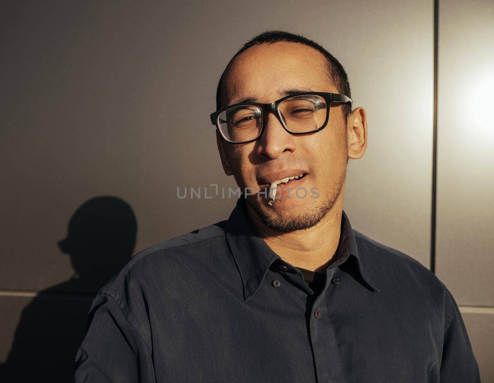 Man smoking a white paper joint close up. Sungles black background