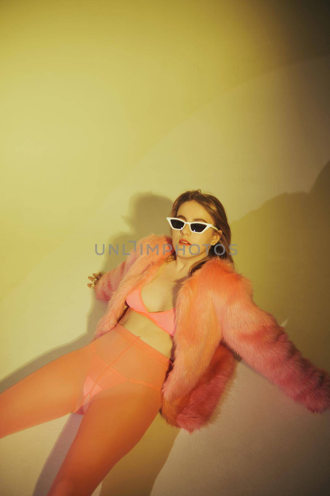 Fashion model in pink suit and sunglasses. Studio shot.