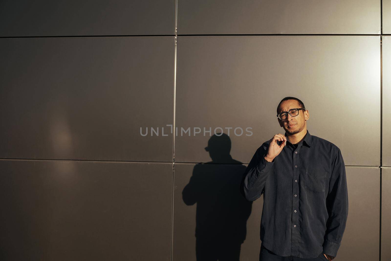 Man smoking a white paper joint close up. Sungles black background