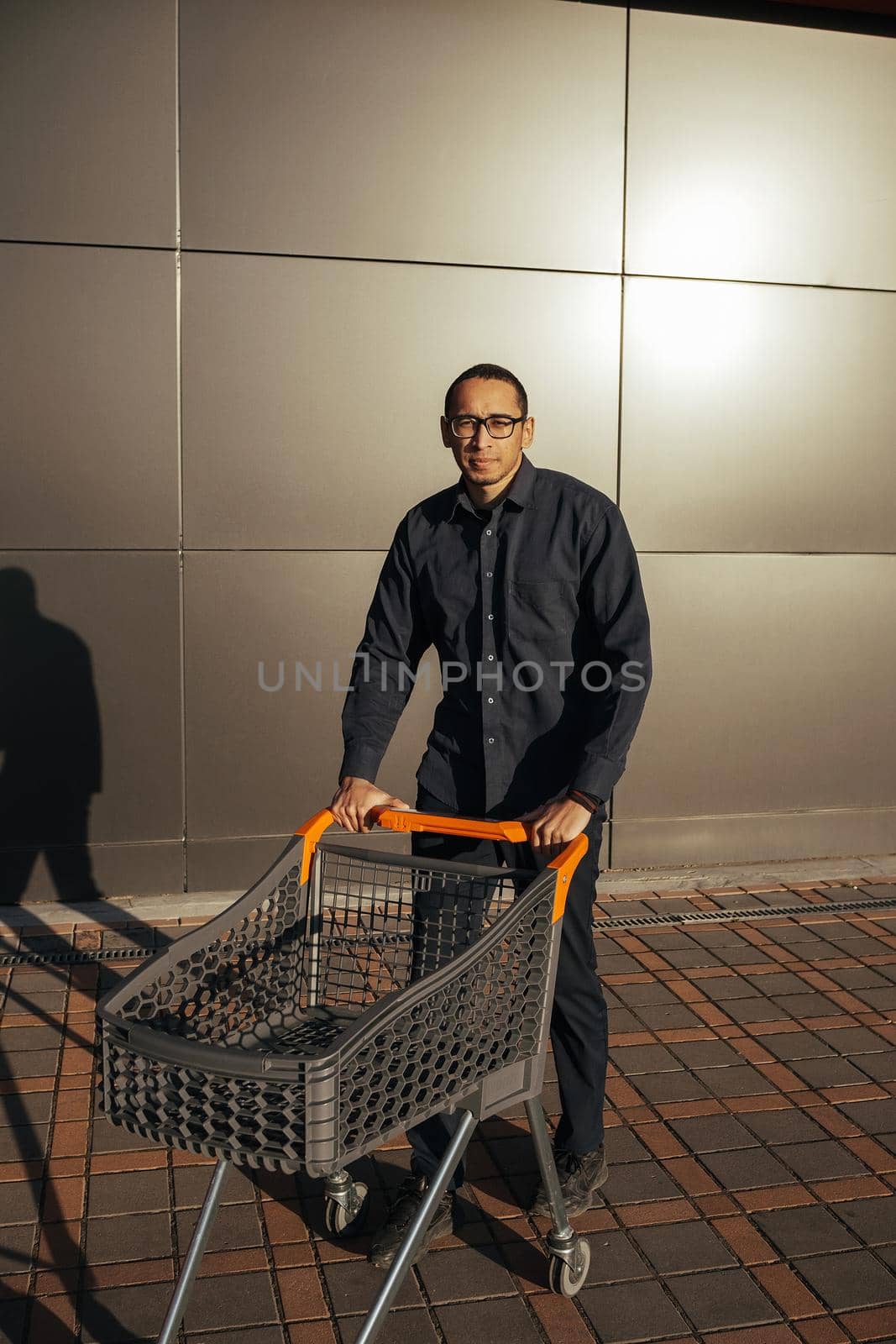 afro shopping with a shopping cart, the guy is shopping near the mall, rejoices and miling, concept: successful purchase