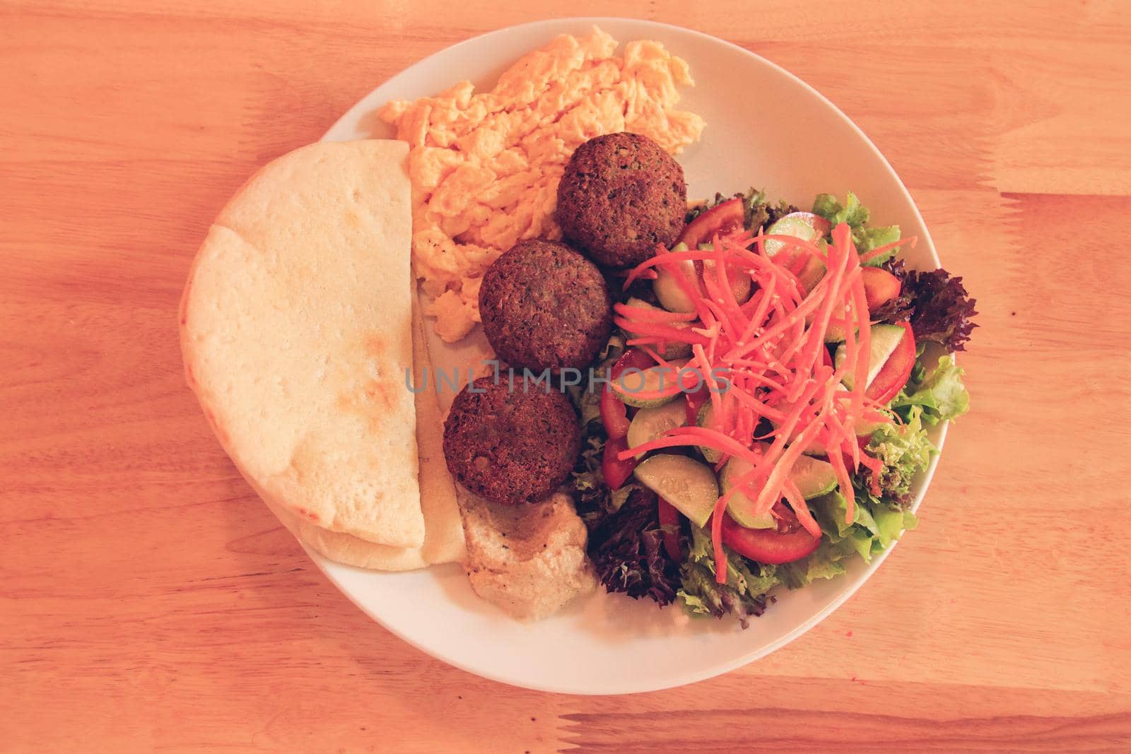 A plate full of falafel balls, pita bread, scrambled eggs and raw vegetable salad for a healthy high protein ovo-vegetarian ketogenic breakfast