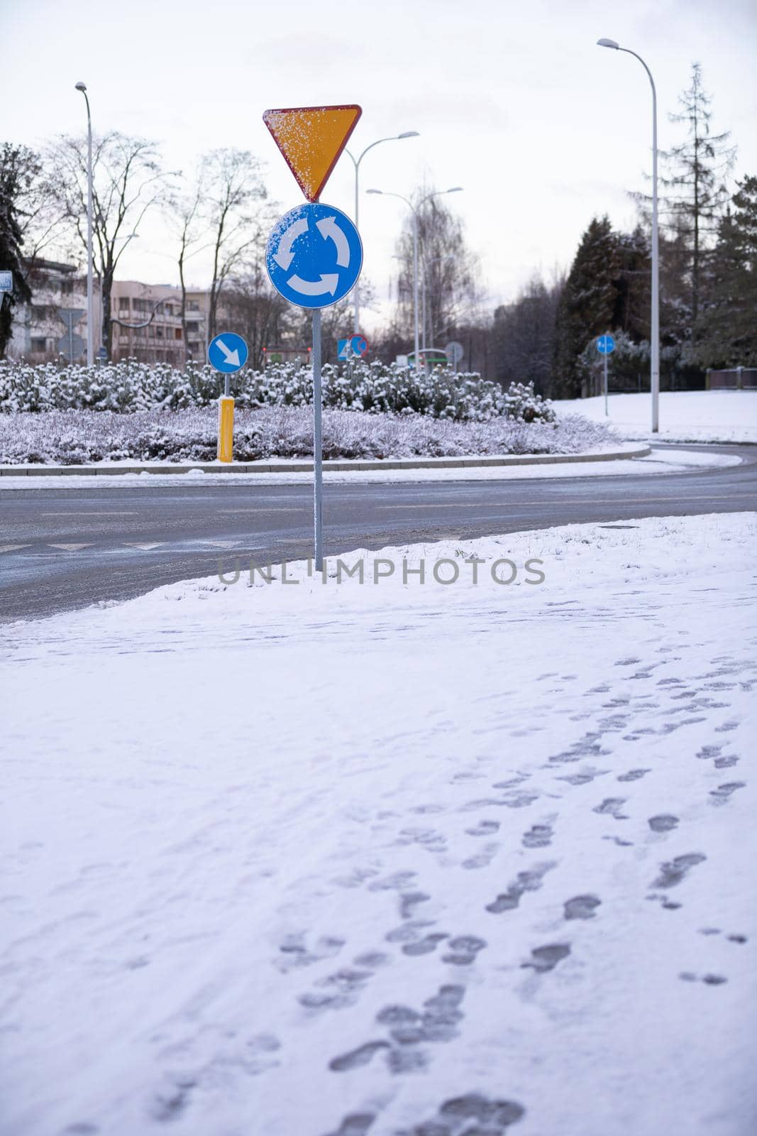 Winter weather covered the street and city sidewalks with ice and snow. Reflected footprints in the snow.