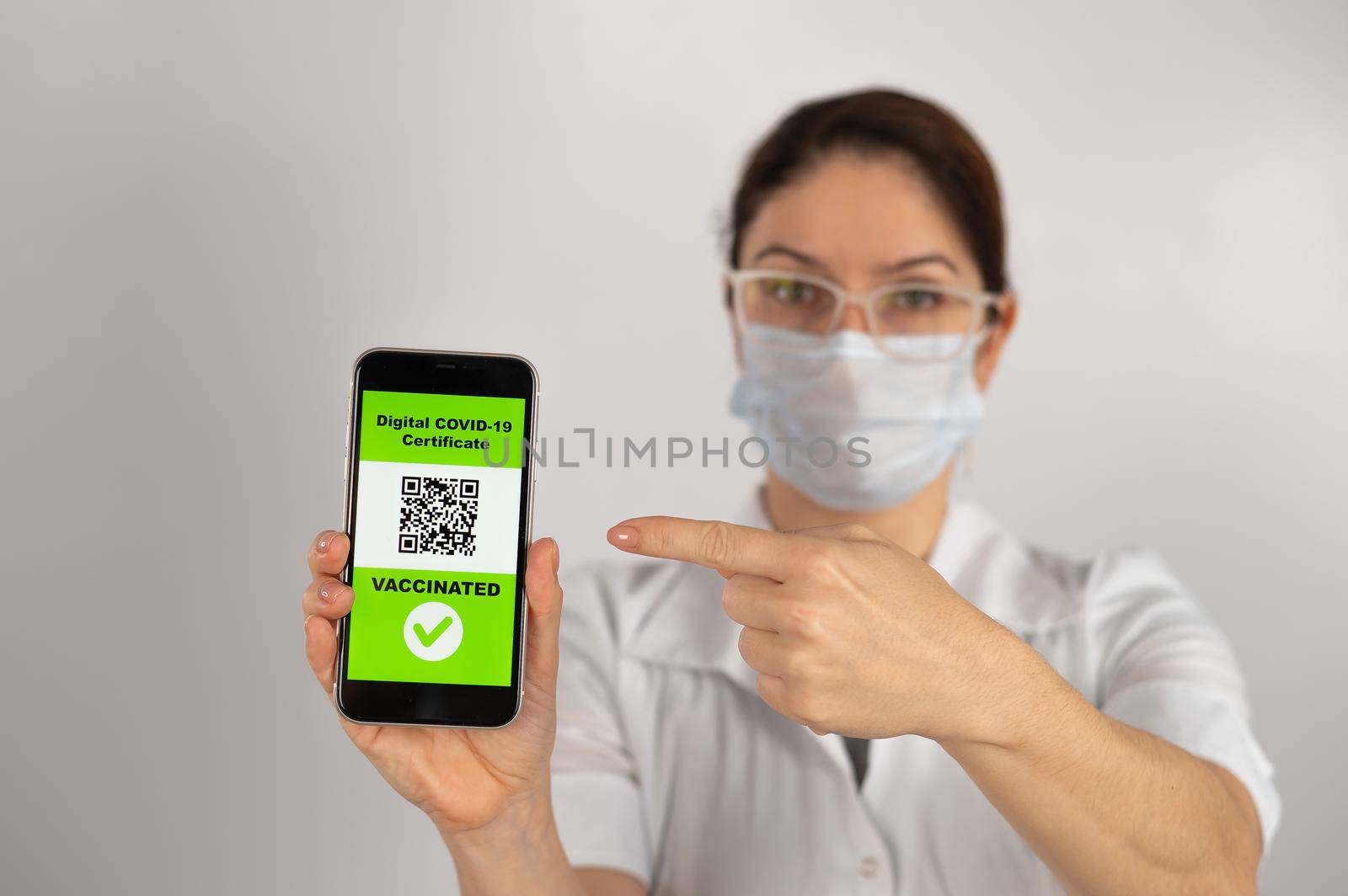 The doctor recommends vaccination and holds a smartphone with a QR code. by mrwed54