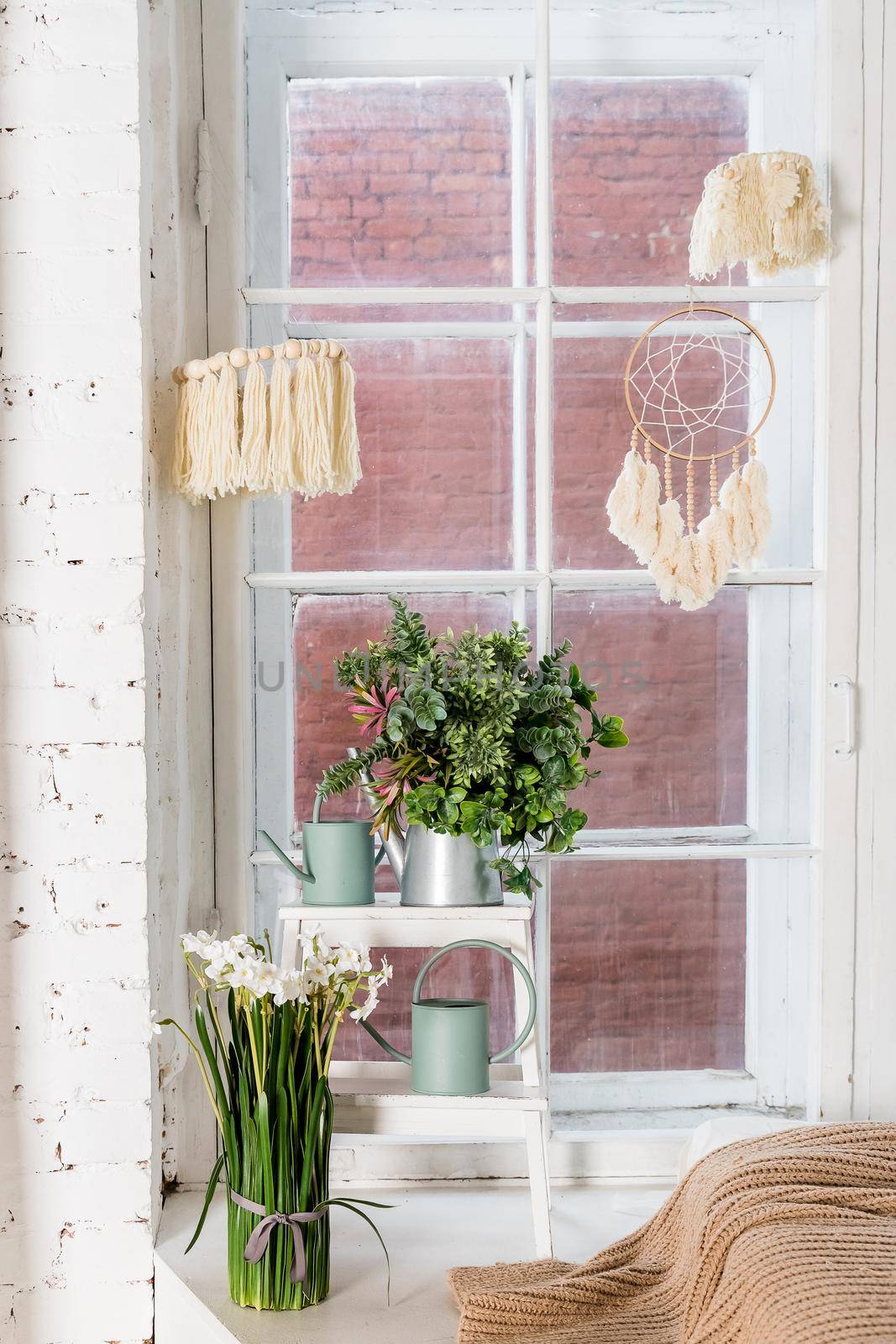 Stylish and modern boho interior of living room with flowers in vase, beige macrame and elegant accessories