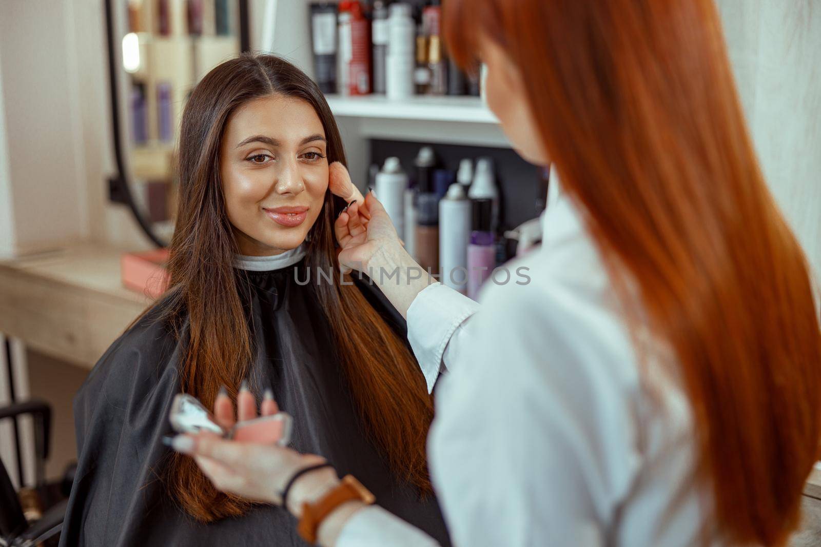 Face of young woman getting blush powder on her cheek with a brush. Beauty salon services