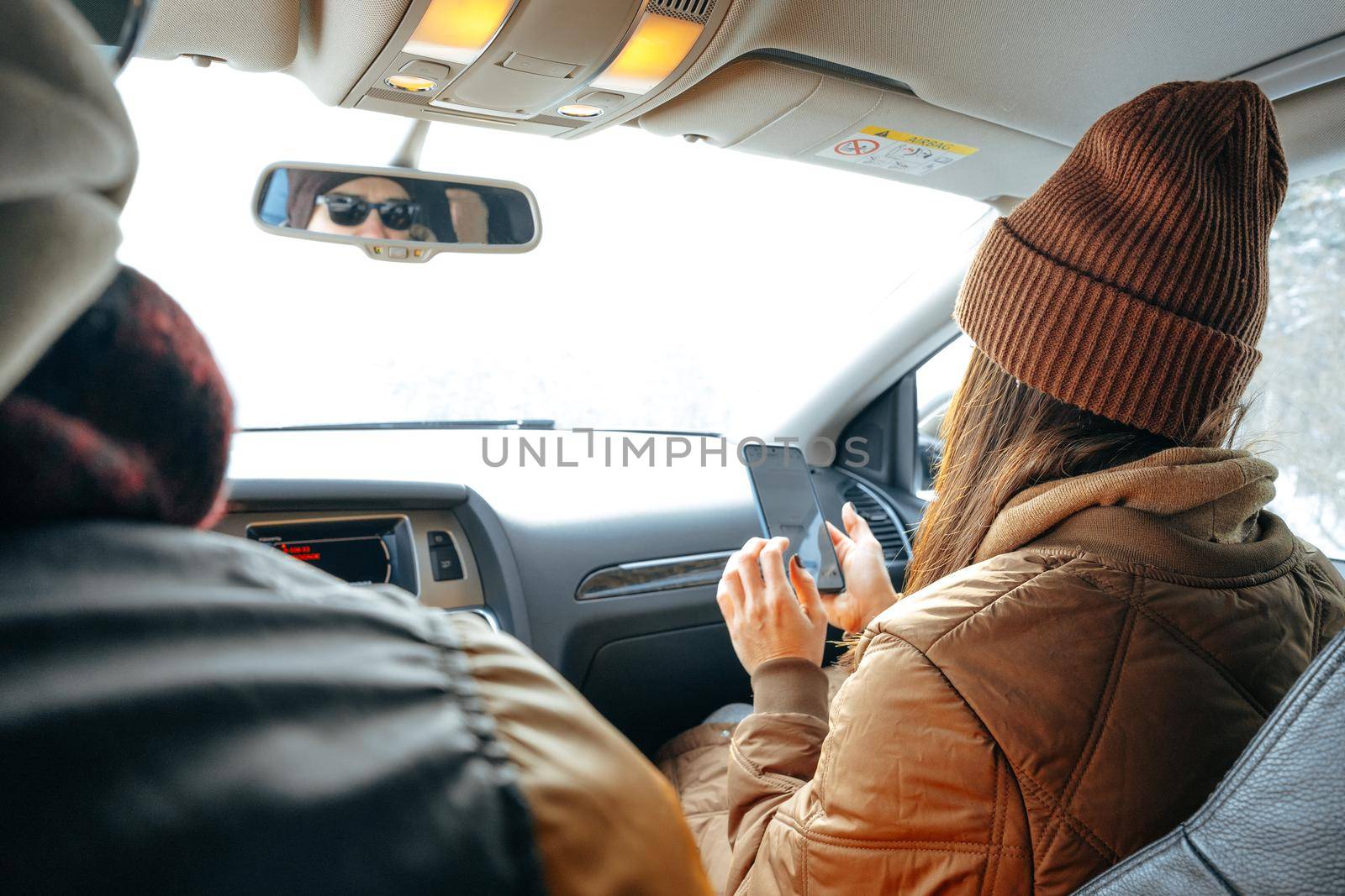 Beautiful young woman wearing warm clothes sitting in car while winter road trip by Fabrikasimf