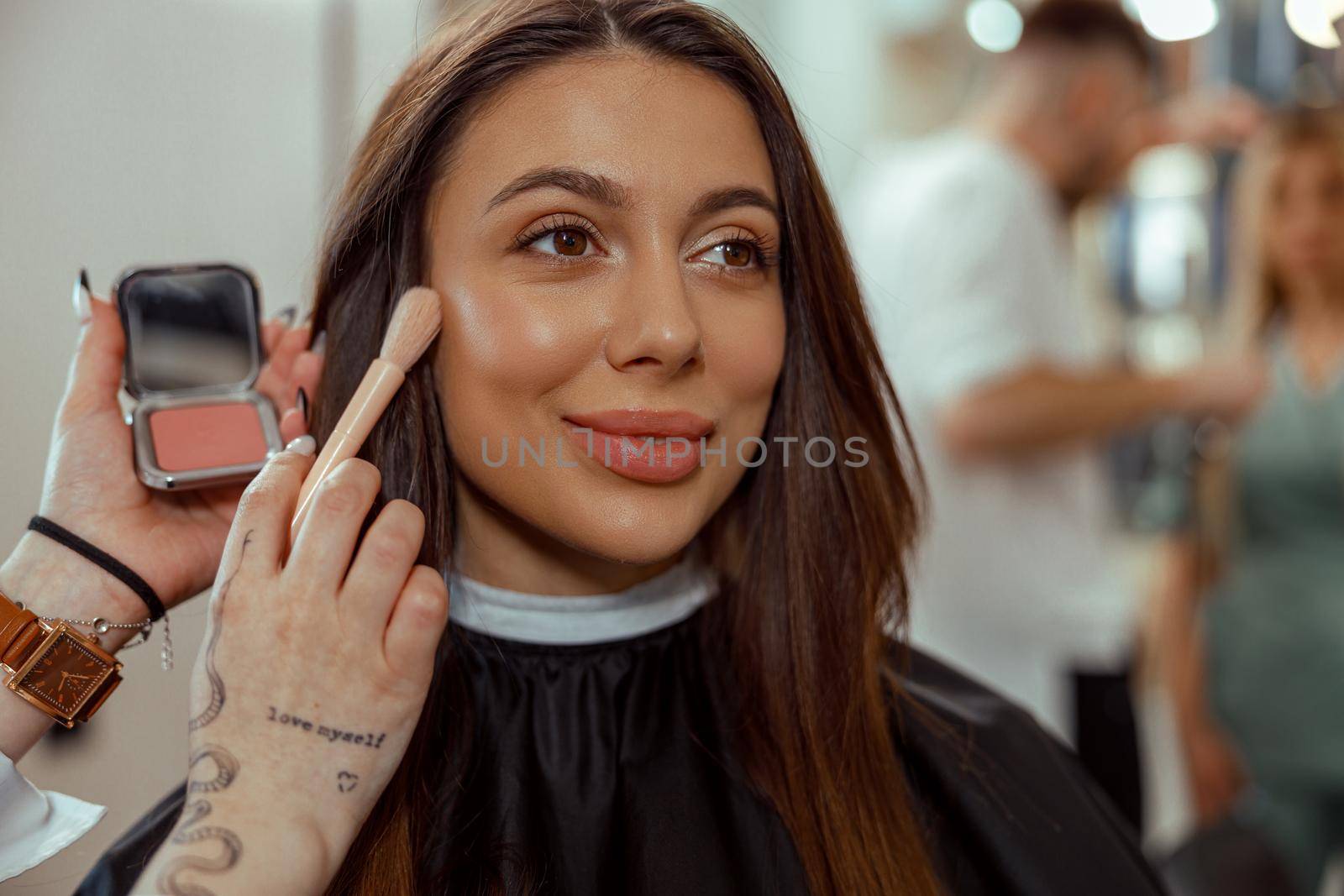 Portrait of smiling woman getting makeup with a brush in beauty salon by Yaroslav_astakhov