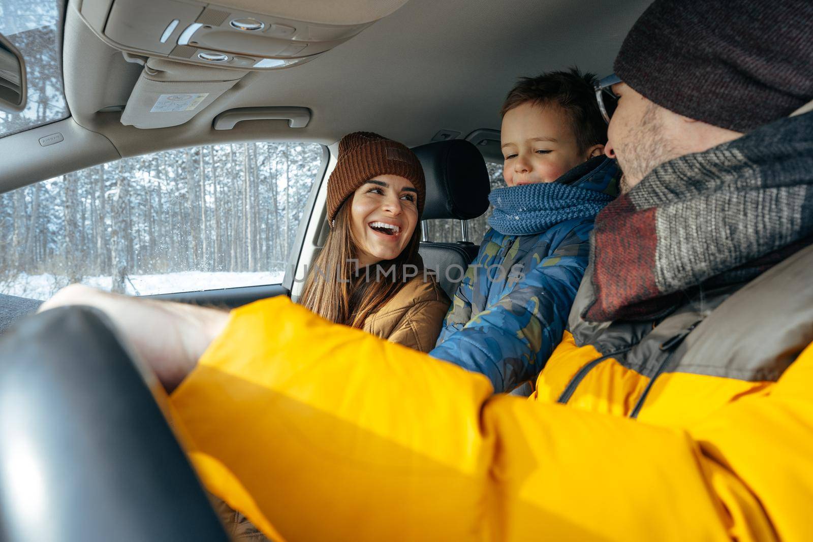 Mother, father and child traveling by car on a vacation to the mountains in winter by Fabrikasimf