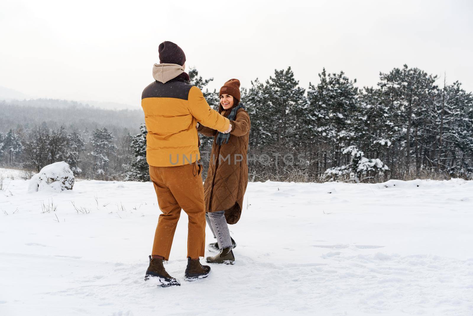 Young couple in love outdoor in snowy winter forest having a walk