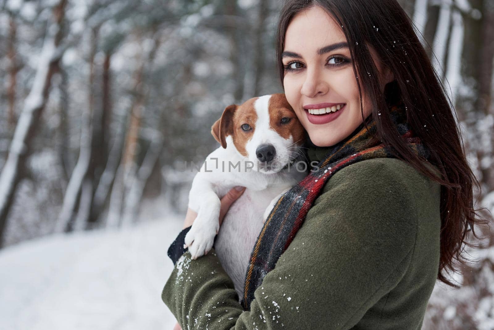 Nice portrait. Smiling brunette having fun while walking with her dog in the winter park.