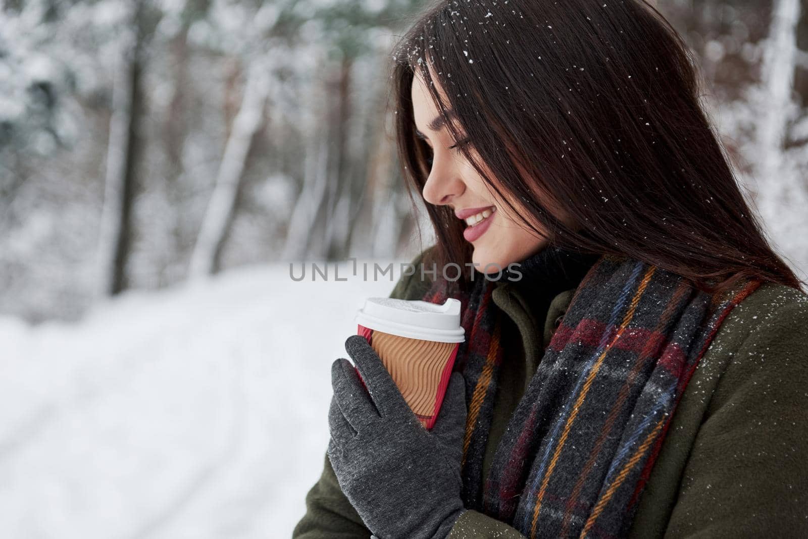 Looks satisfied. Girl in warm clothes with cup of coffee have a walk in the winter forest by Standret