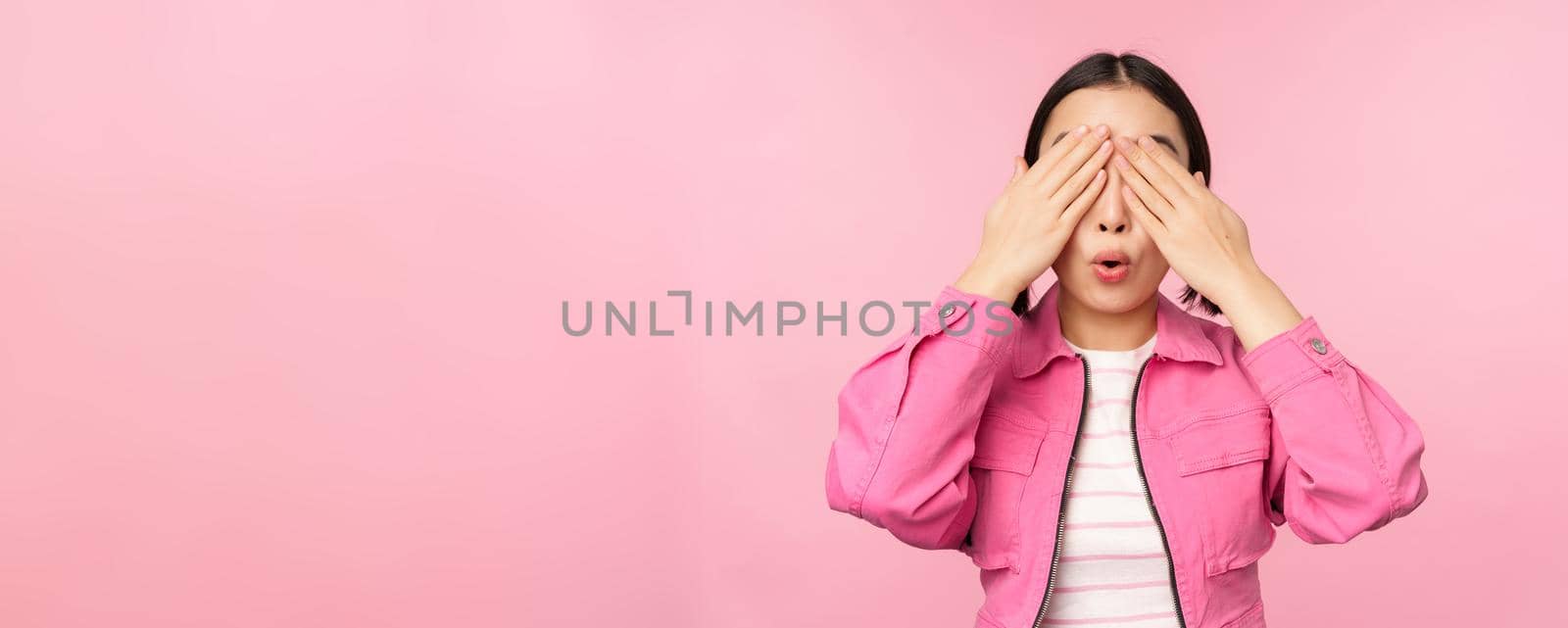 Surprise and celebration. Portrait of asian happy girl close eyes, waiting for gift, anticipating something, standing blindsided against studio background. Copy space