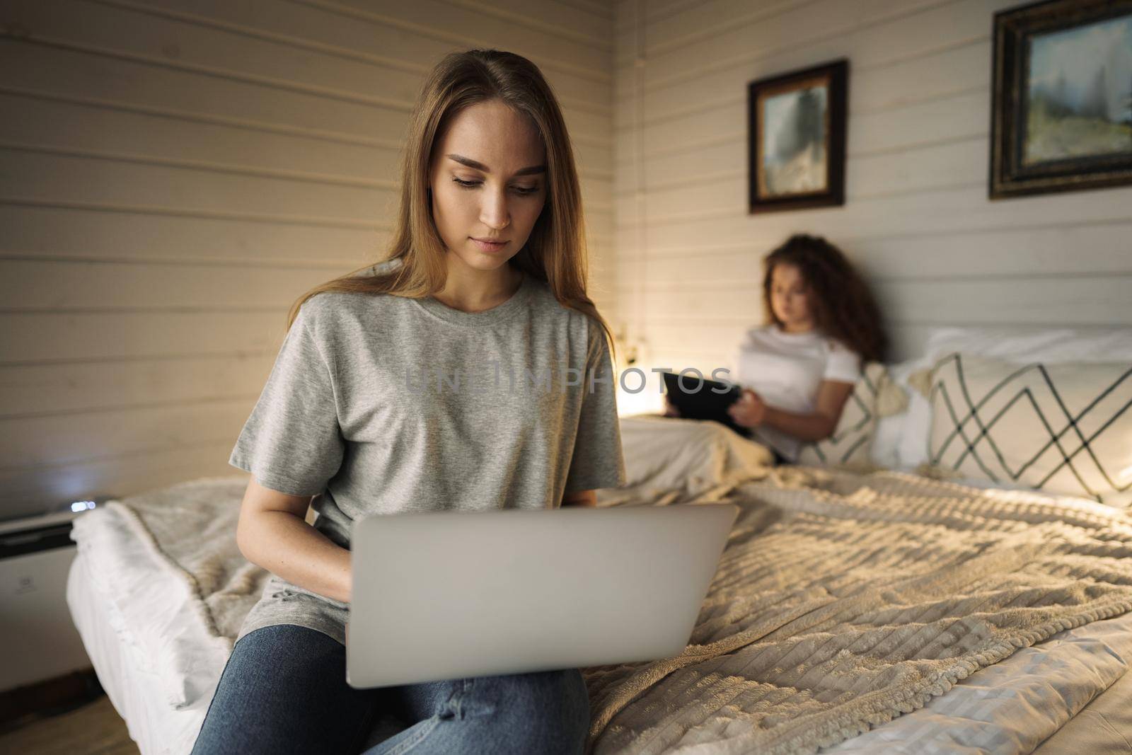 Two beautiful women lying in bed, holding and watching laptop