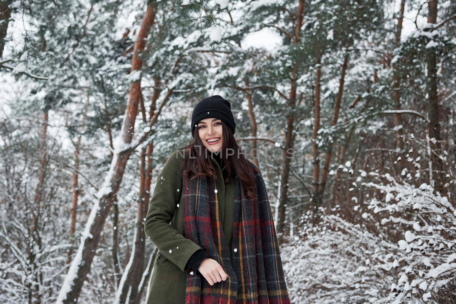 Fun and happy. Cheerful young girl in warm clothes have a walk in the winter forest at daytime.