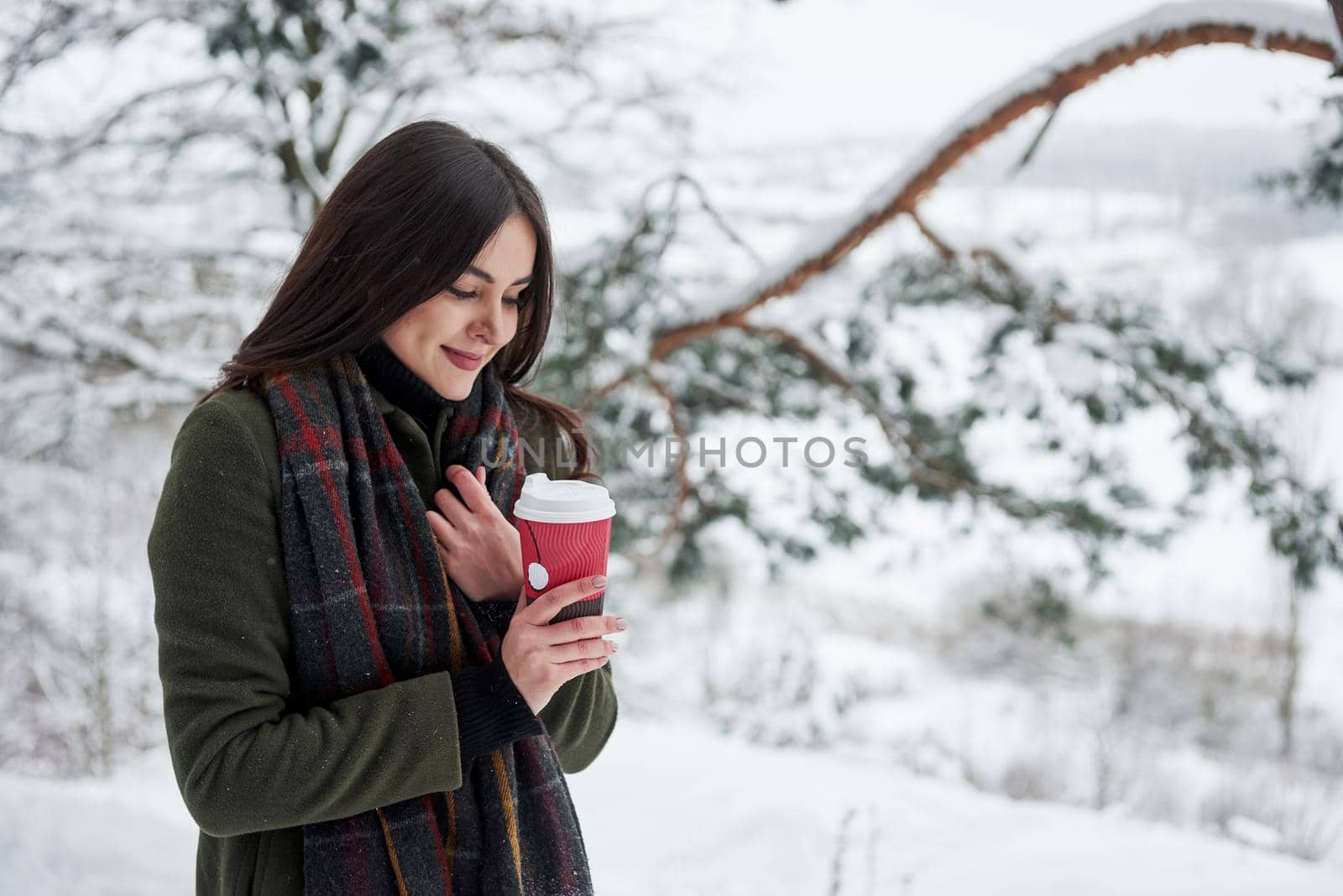 Enjoying fresh drink. Girl in warm clothes with cup of coffee have a walk in the winter forest by Standret