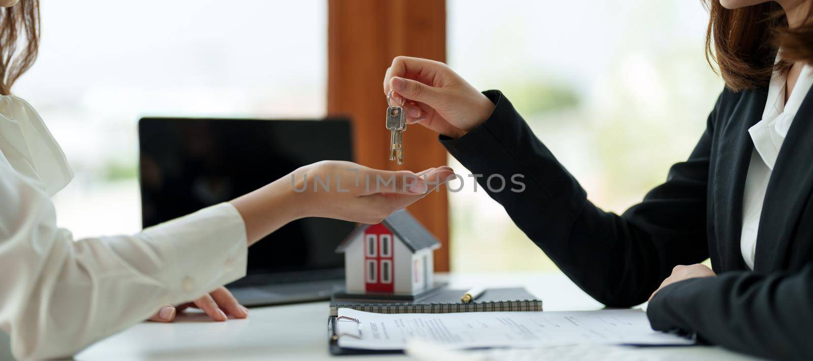 real estate agent holding house key to his client after signing contract agreement in office,concept for real estate, moving home or renting property by nateemee