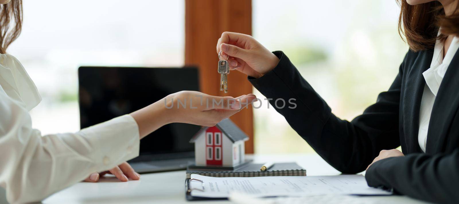 real estate agent holding house key to his client after signing contract agreement in office,concept for real estate, moving home or renting property.