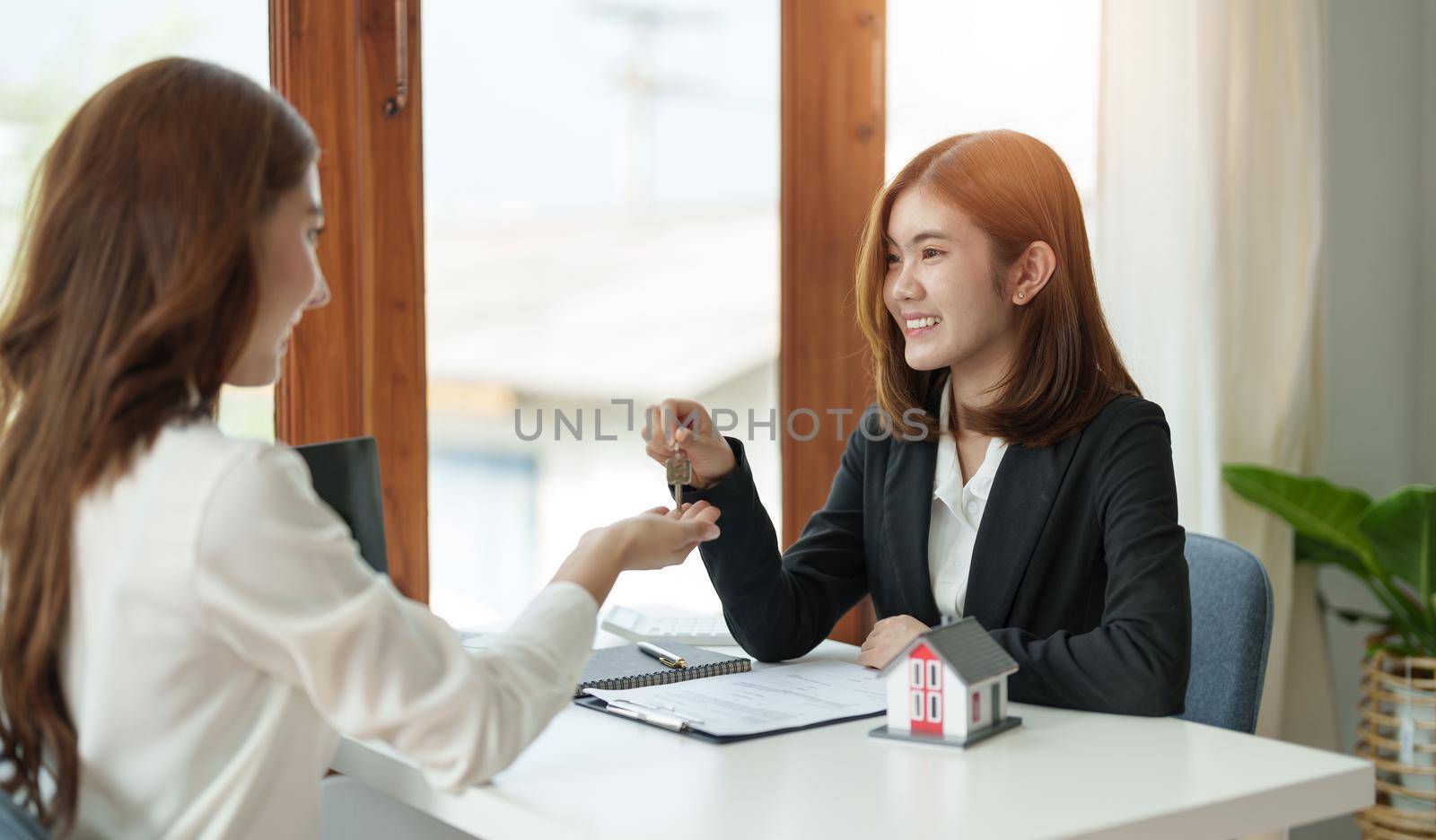 real estate agent holding house key to his client after signing contract agreement in office,concept for real estate, moving home or renting property.