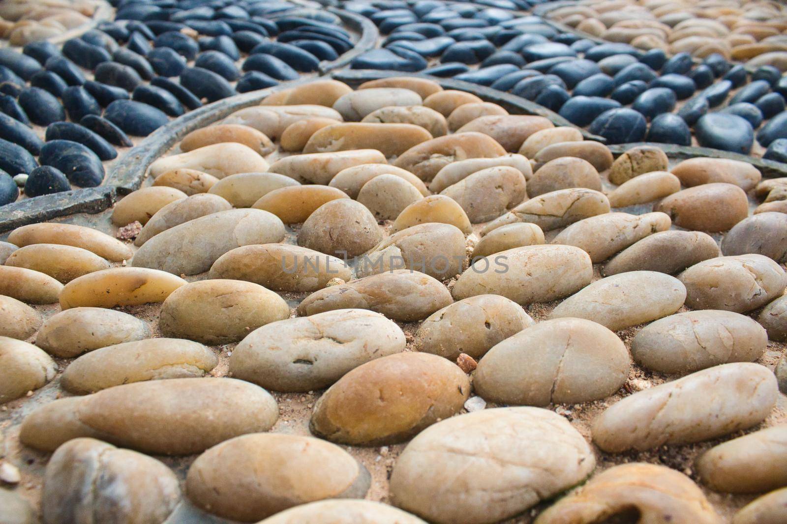 Yellow white polished river stones inset in a mosaic pattern on a walkway