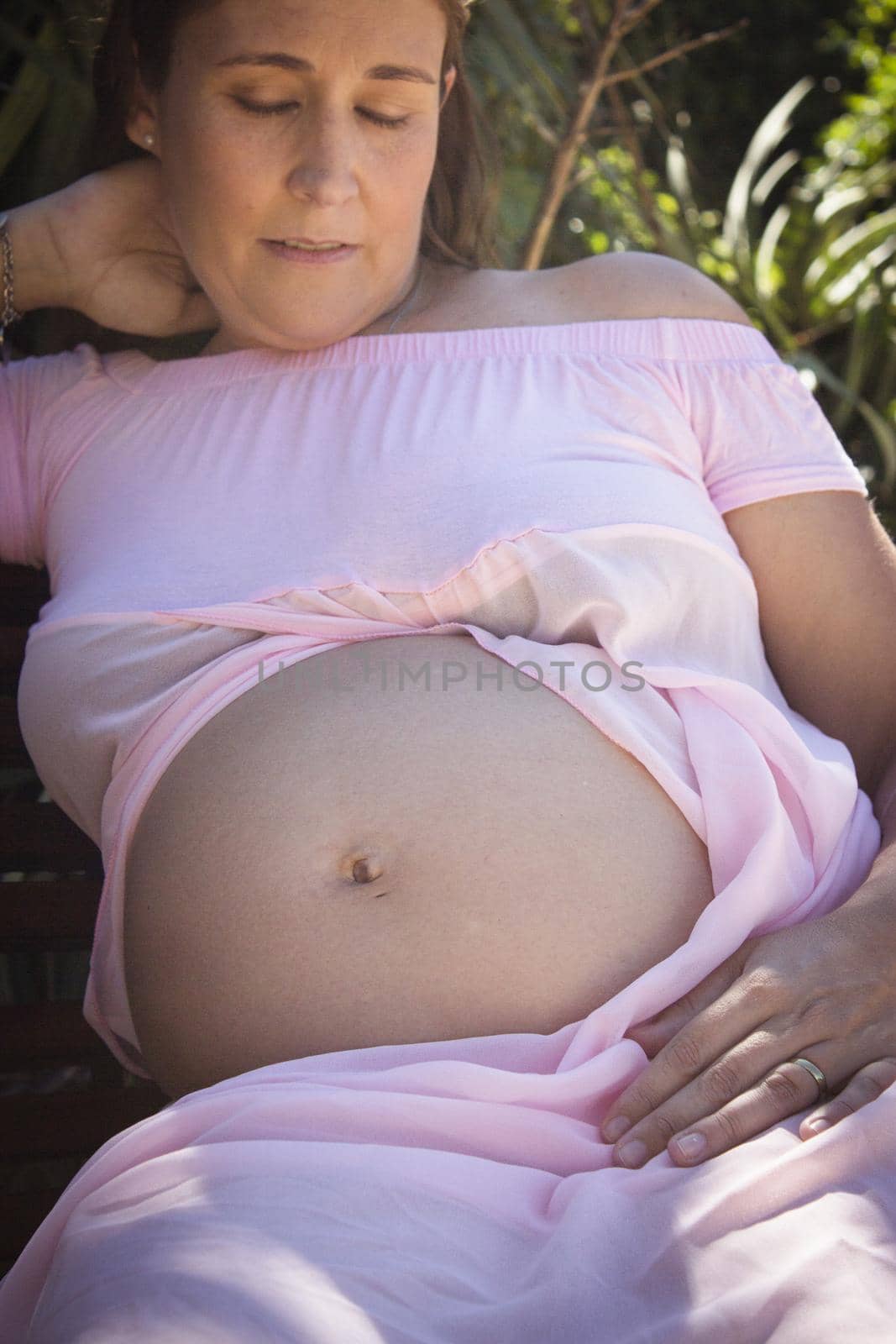 Seven months pregnant woman in pink dress half lying down by GemaIbarra