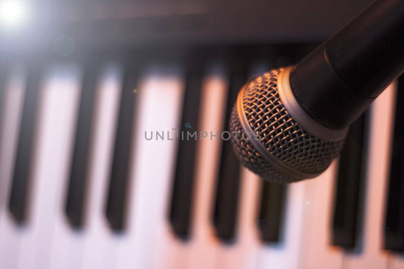 Microphone over piano keys in dim light. No people