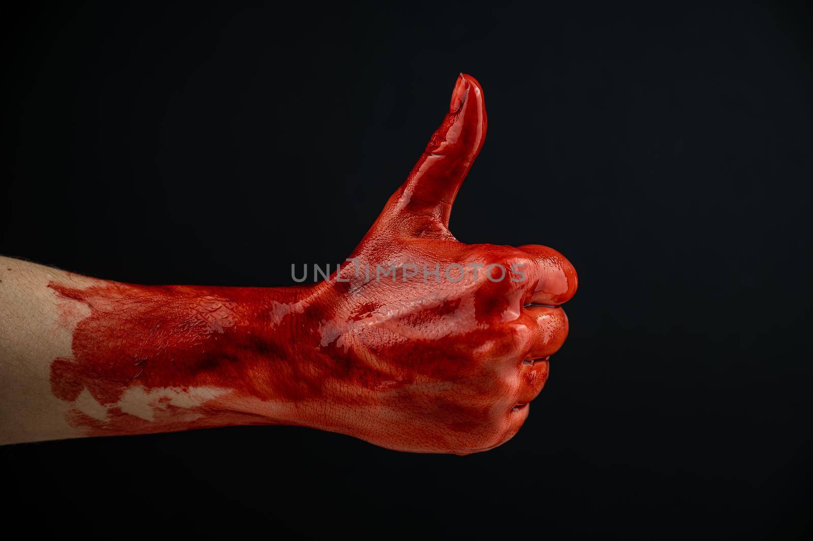 A woman's hand stained with blood shows a thumbs up on a black background. by mrwed54