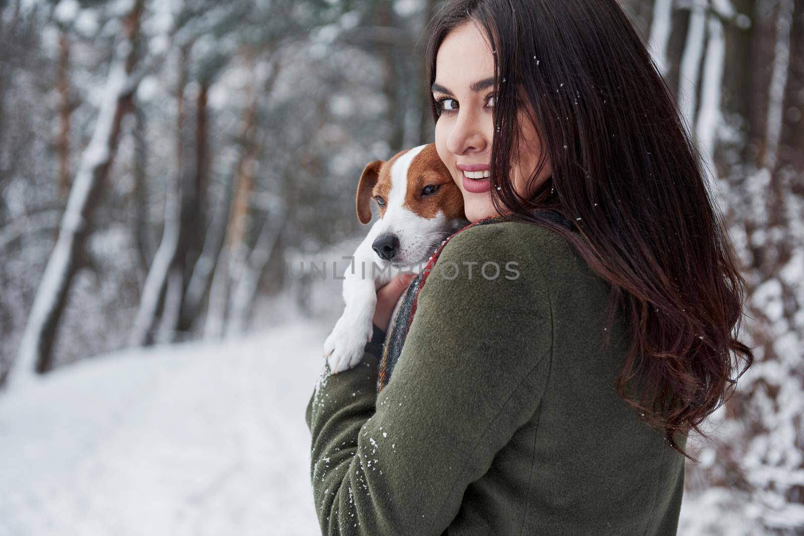 Cheerful mood. Smiling brunette having fun while walking with her dog in the winter park.