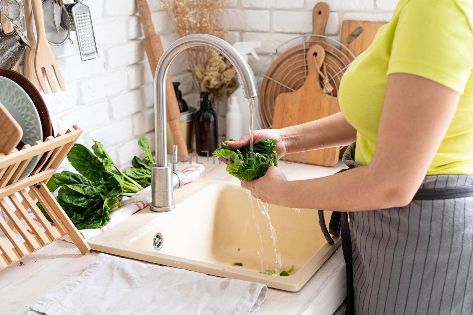 Woman Washing spinach in the Kitchen Sink by Desperada