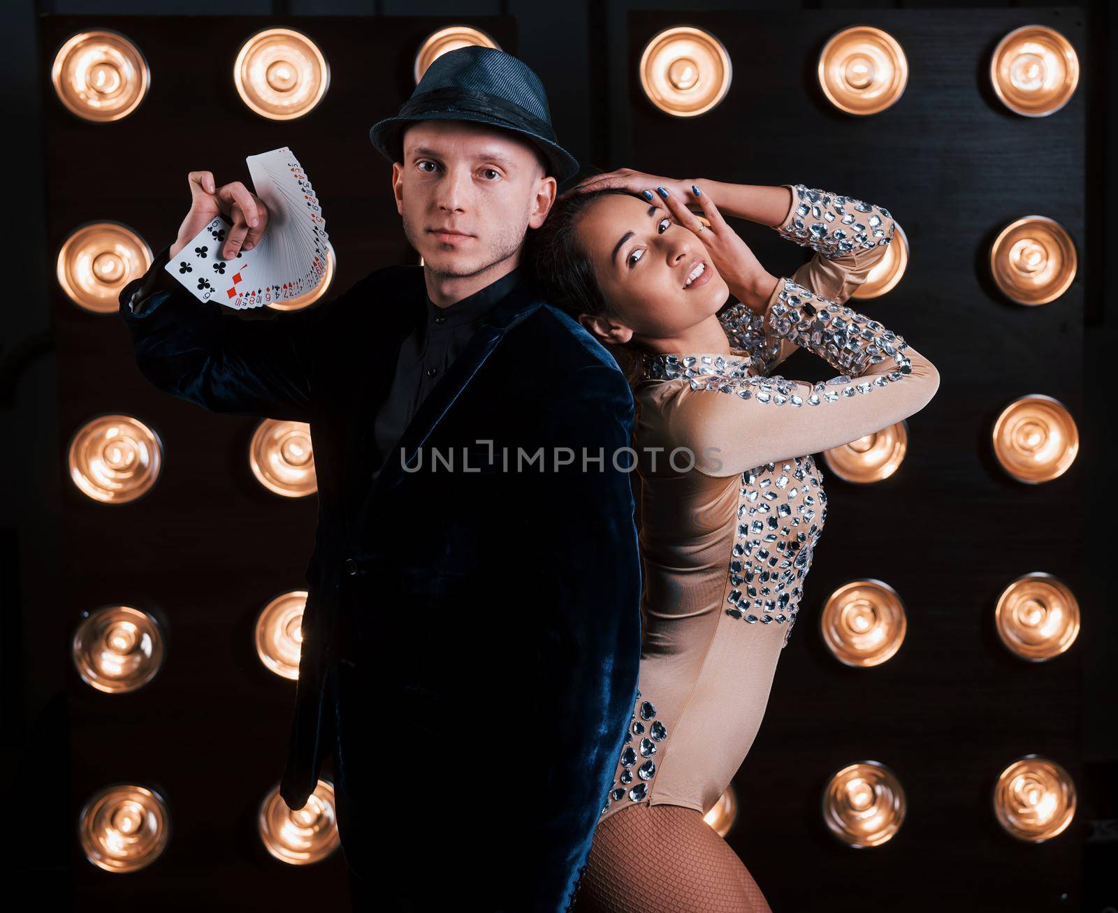 Guy showing the cards, girl is leaning on him. Happy couple posing for the portrait. Family business of magician tricks and shows.