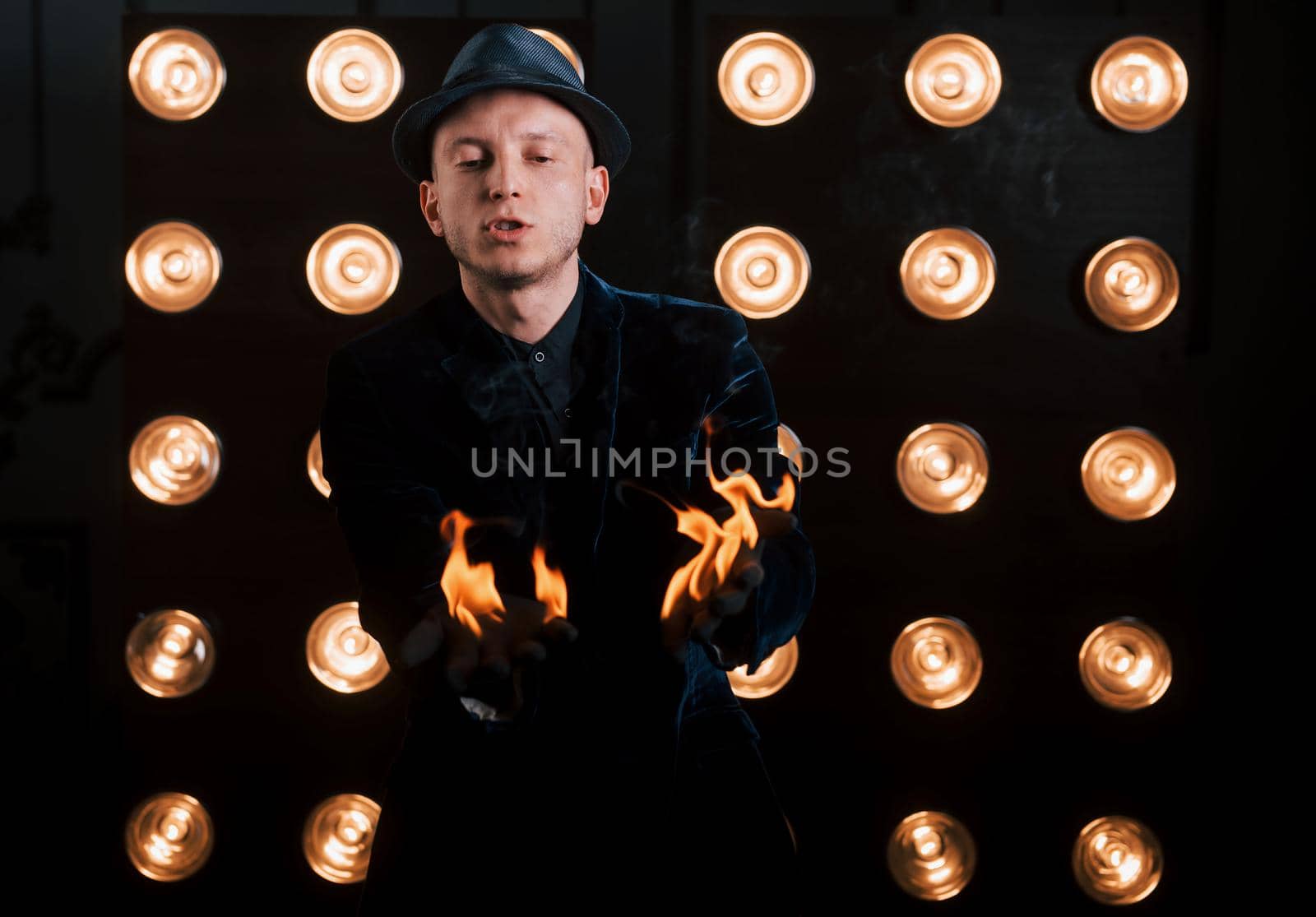 Burning nice. Professional illusionist in black hat, shirt and gloves playing with fire.