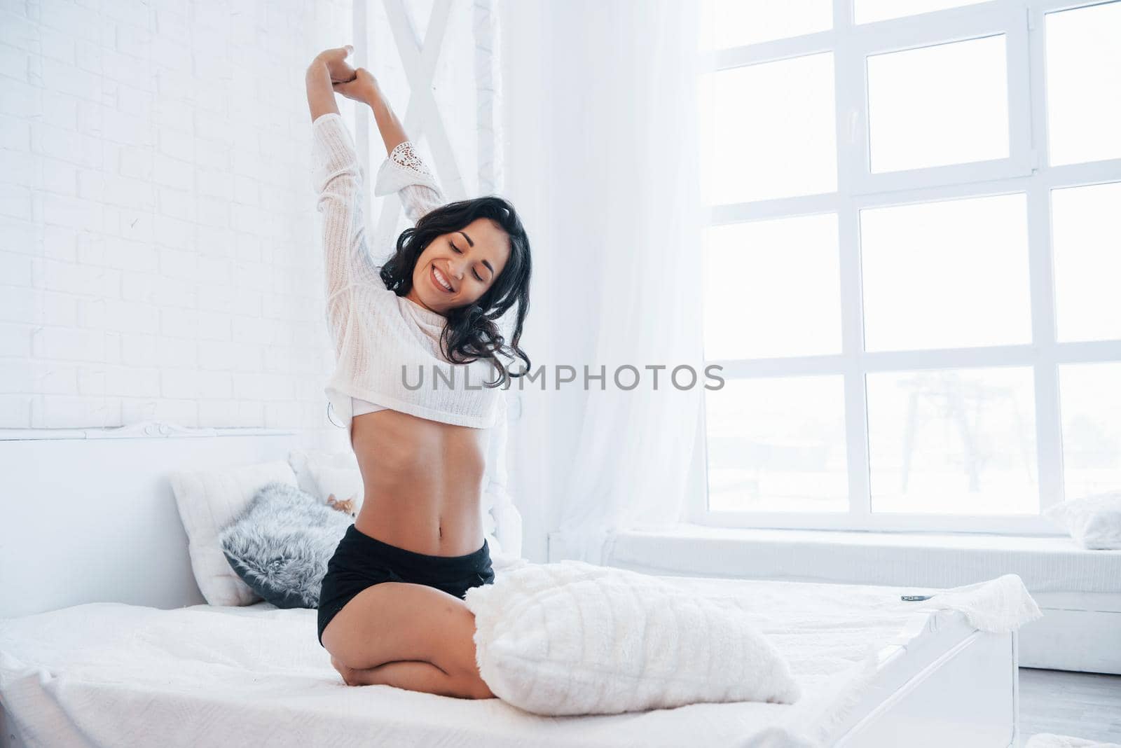 Nice morning with gorgeous woman. Brunette having a rest on the white couch in her bedroom at daytime.