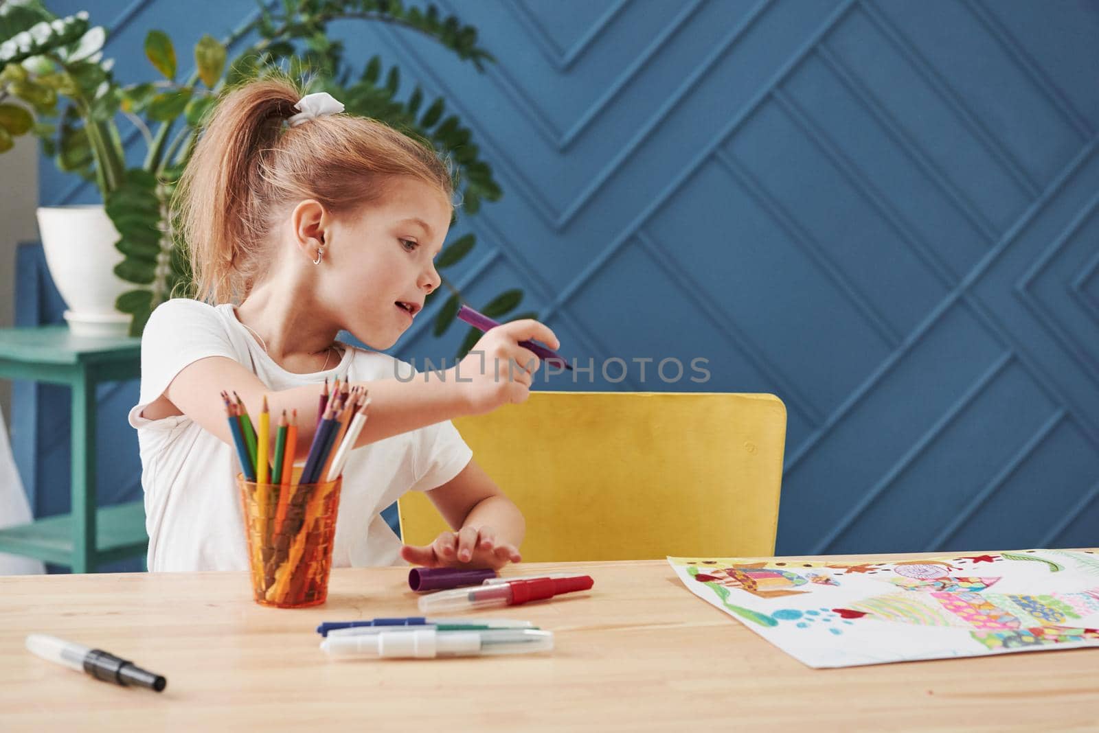 Need to make some corrections. Cute little girl in art school draws her first paintings by pencils and markers.