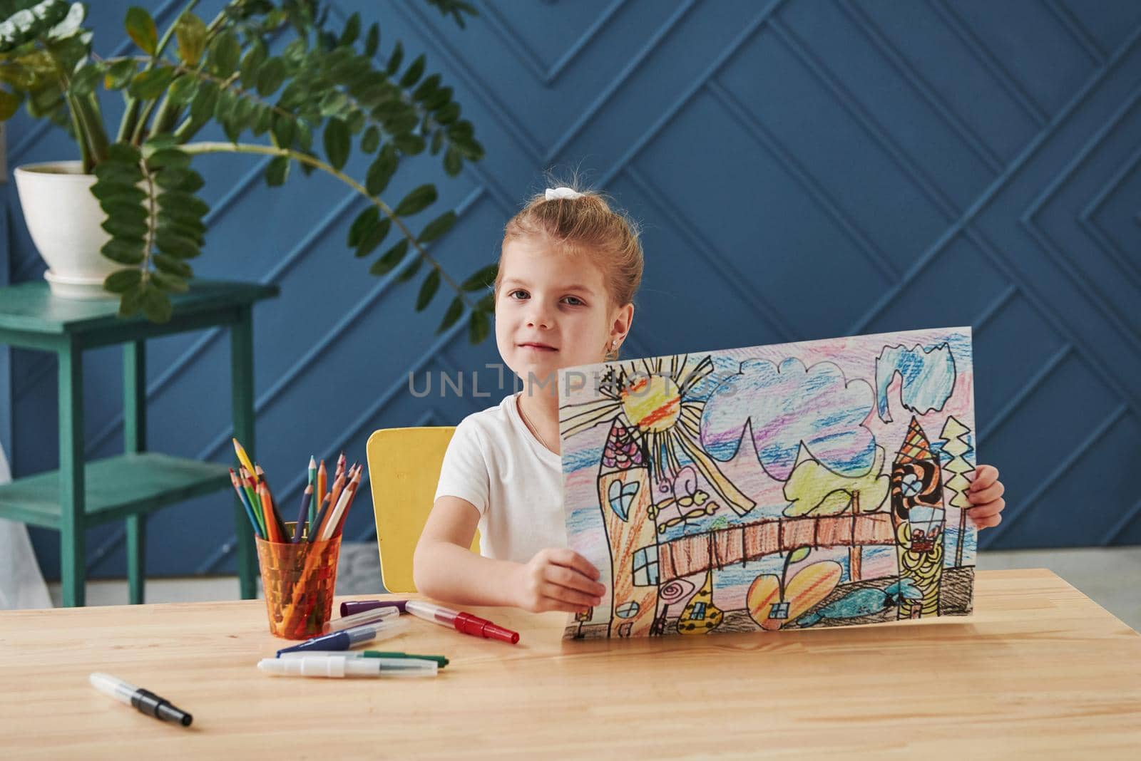 Take a look at that picture. Cute little girl in art school shows her first paintings drawn by pencils and markers.