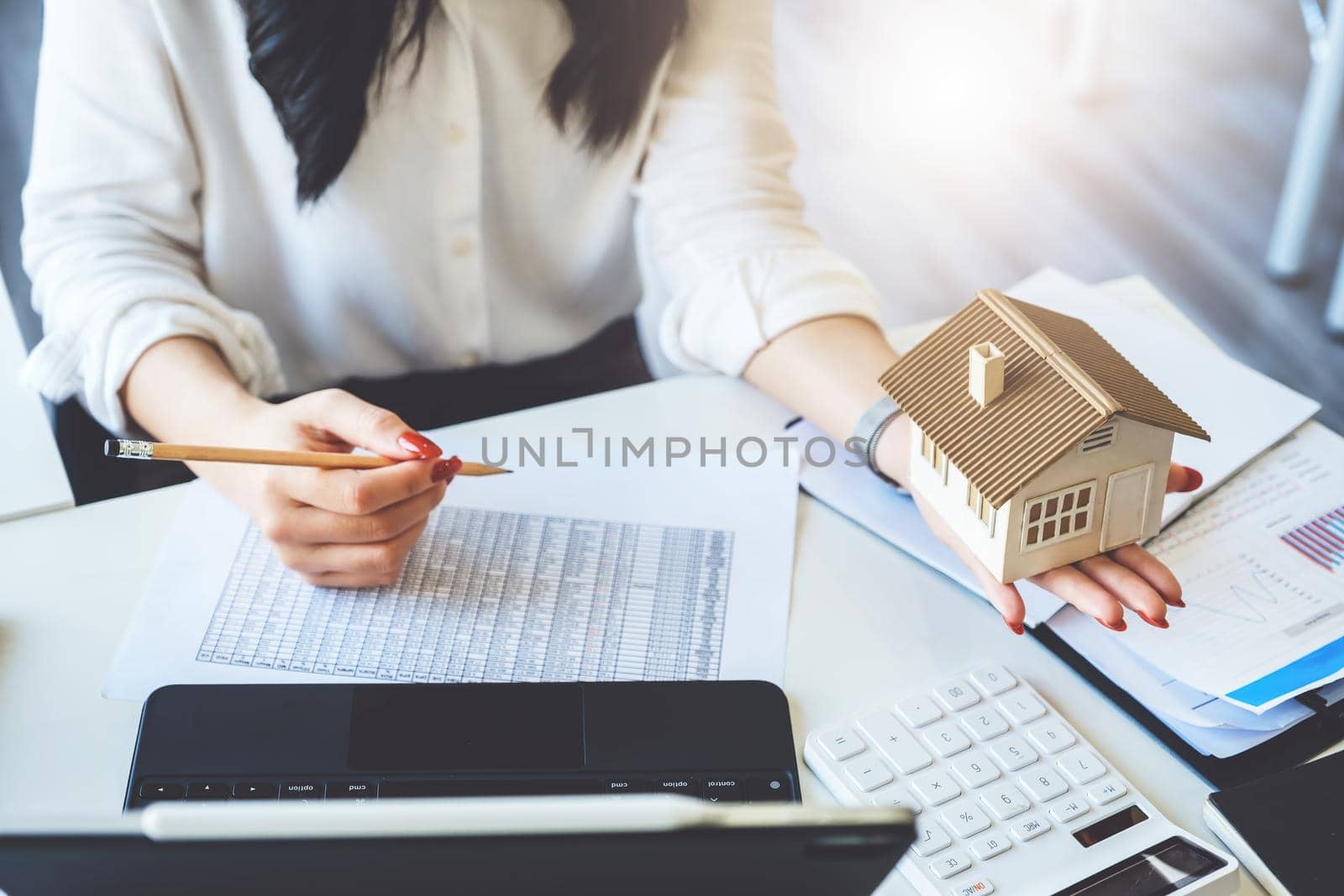 Accountant, businessman, real estate agent, Asian business woman handing model house to customers along with house interest calculation documents for customers to sign