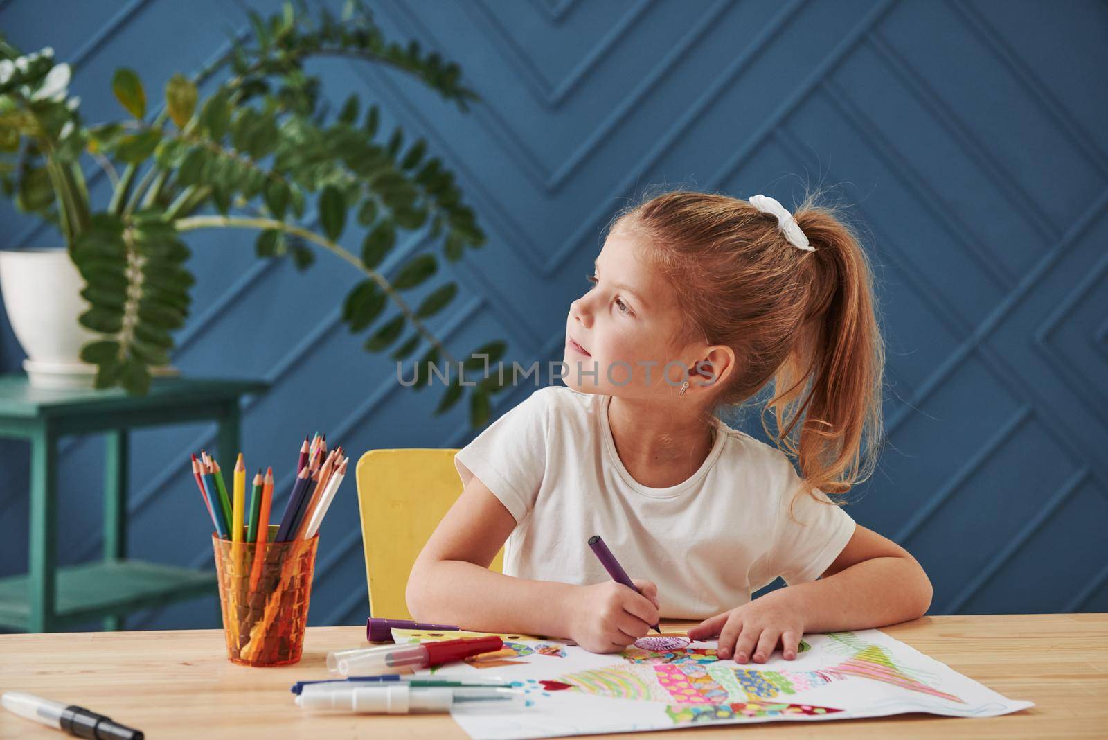 Searching for the ideas. Cute little girl in art school draws her first paintings by pencils and markers.
