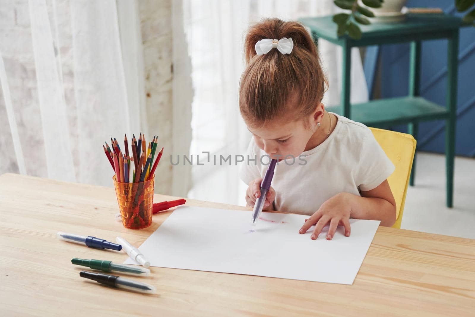 Starting new picture. Cute little girl in art school draws her first paintings by pencils and markers.