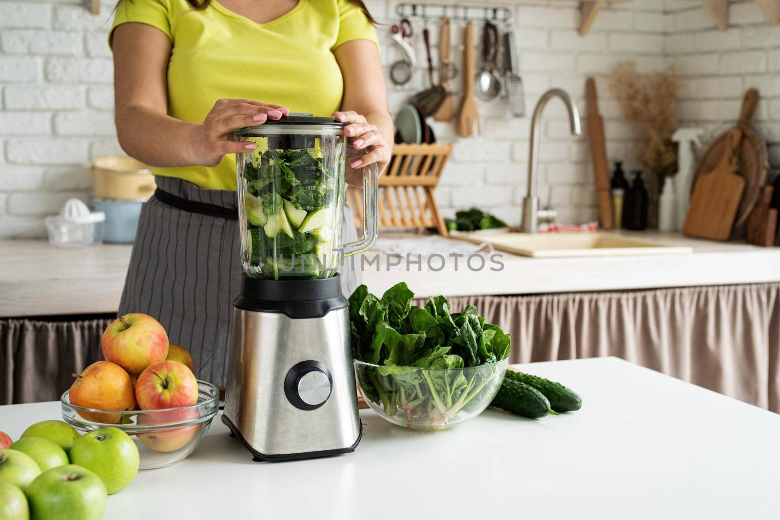 Preparing healthy foods. Healthy eating and dieting. Young brunette woman making green smoothie at home kitchen