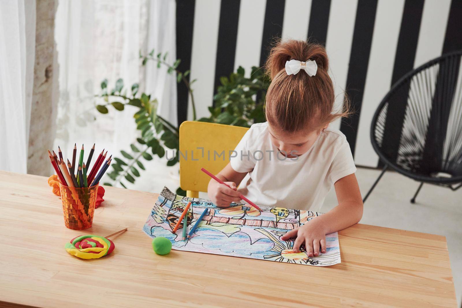 Concentrated at work. Cute little girl in art school draws her first paintings by pencils and markers.