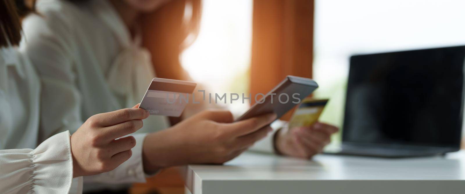 Close up two asian girlfriends shopping online with smart phone and credit card at home. by nateemee