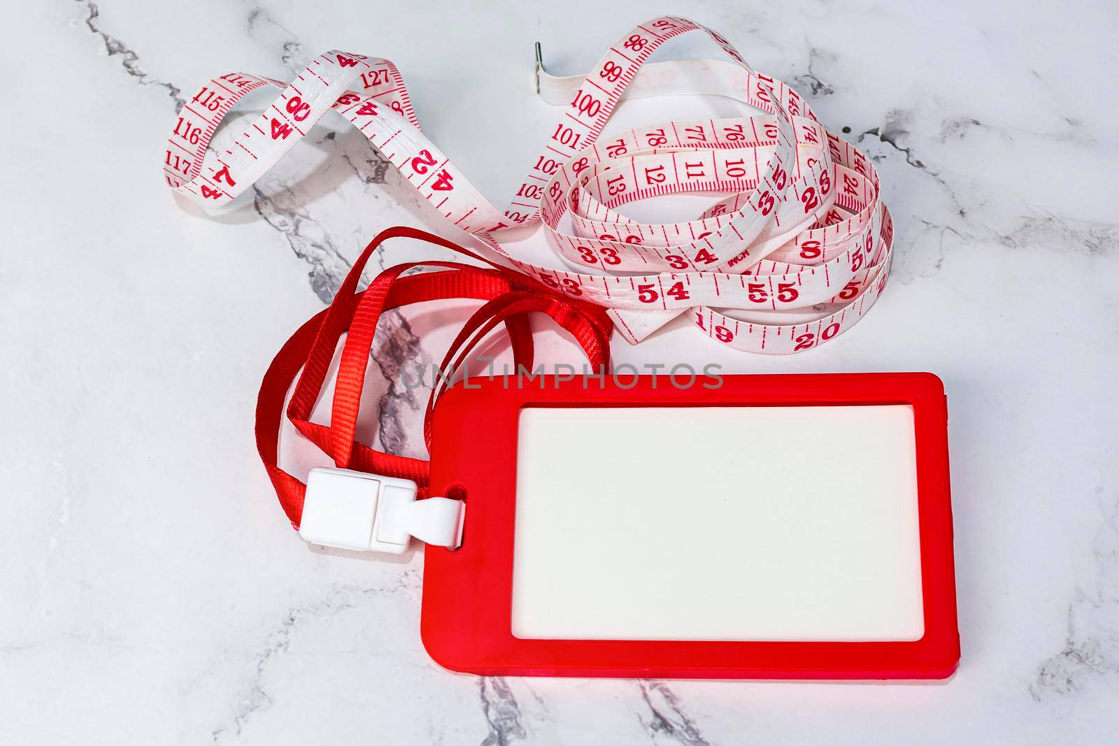 Red name tag with measure tap on white desk. Healthy and diet concept. Copy space.