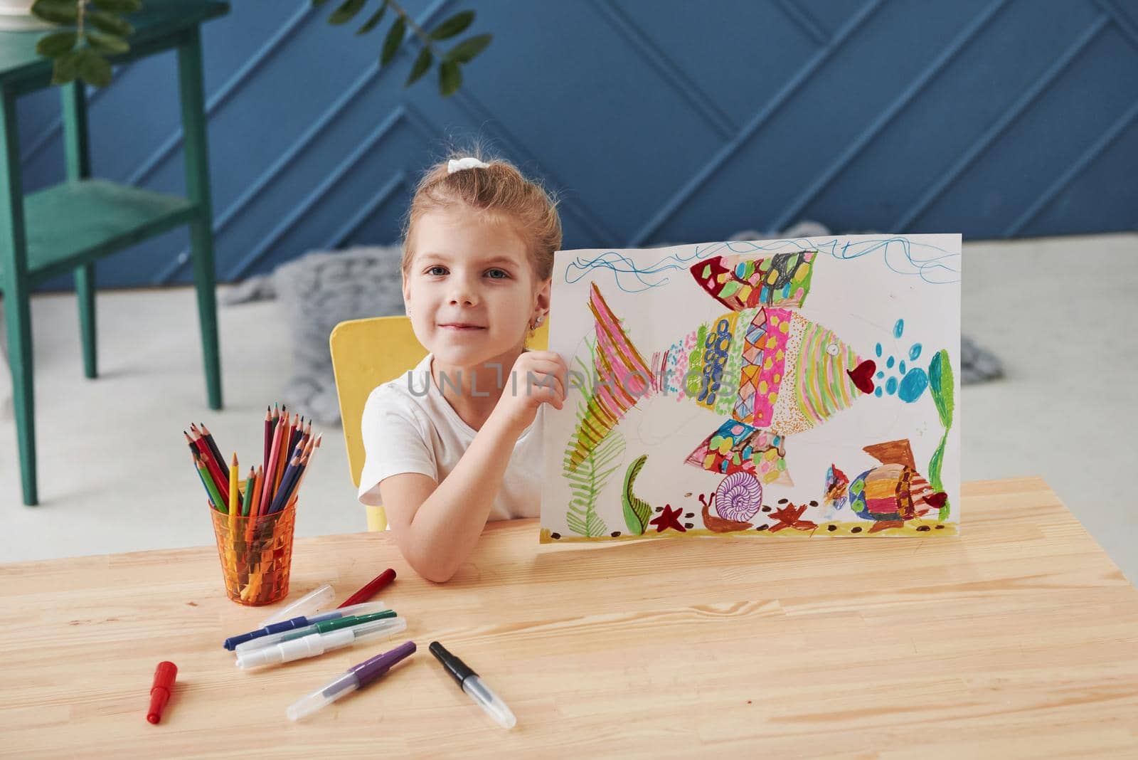 Good beginnings. Cute little girl in art school shows her first paintings drawn by pencils and markers.