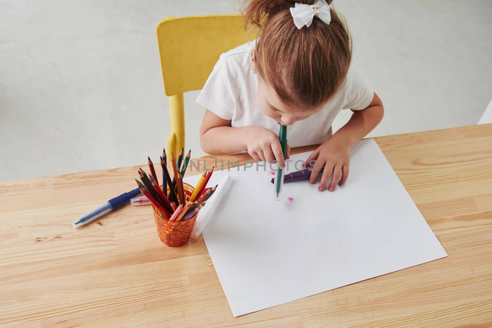 Some kind of art techique. Cute little girl in art school draws her first paintings by pencils and markers.