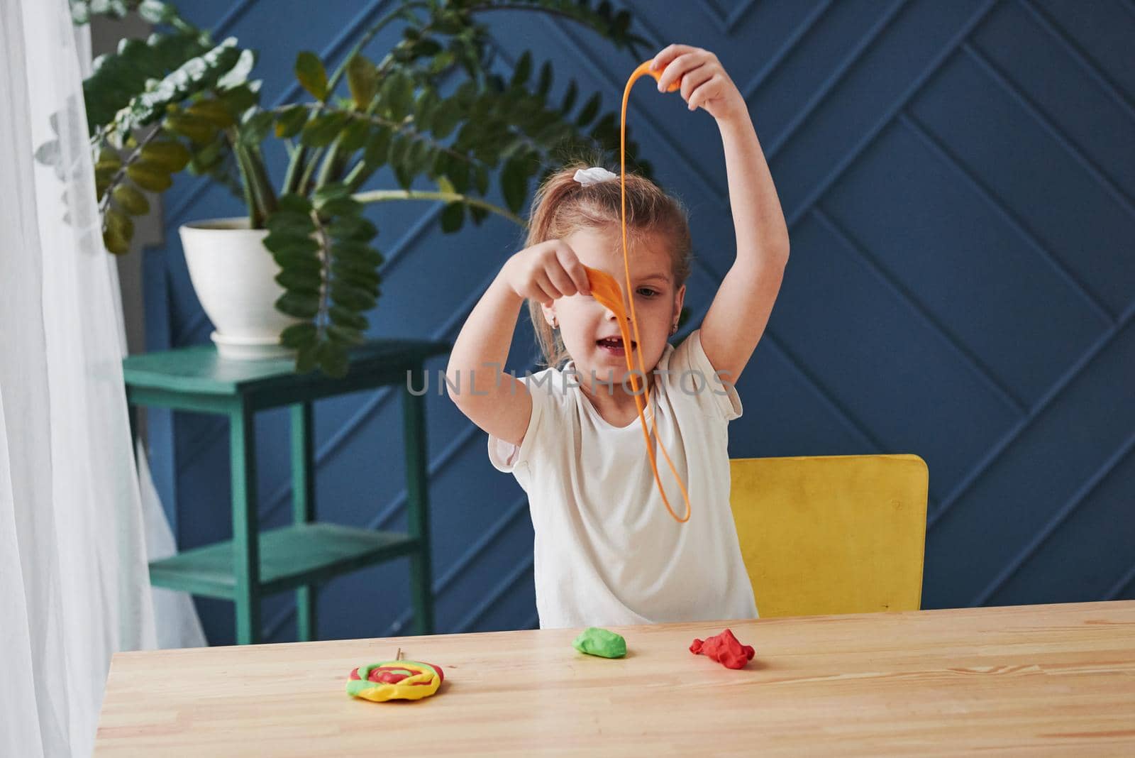 Having some fun. Children playing with colored plasticine on the wooden table at home.