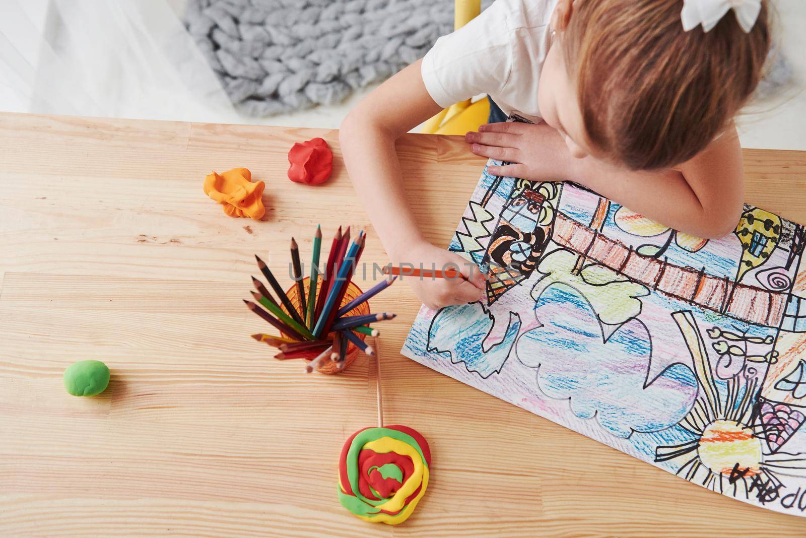 Top view. Cute little girl in art school draws her first paintings by pencils and markers.